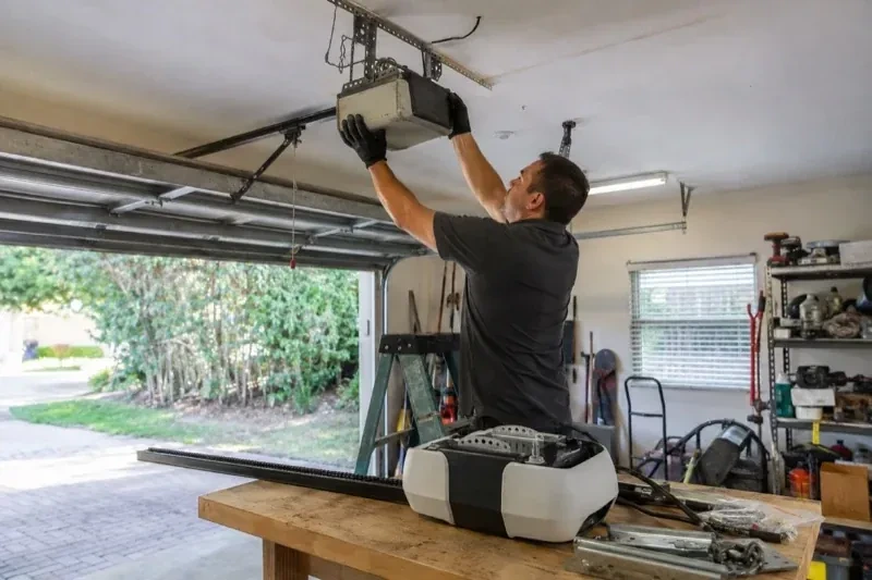 Person holding an overhead garage-door opener beside another opener and hardware on a workbench — Garage Door Opener Replacement, Brampton